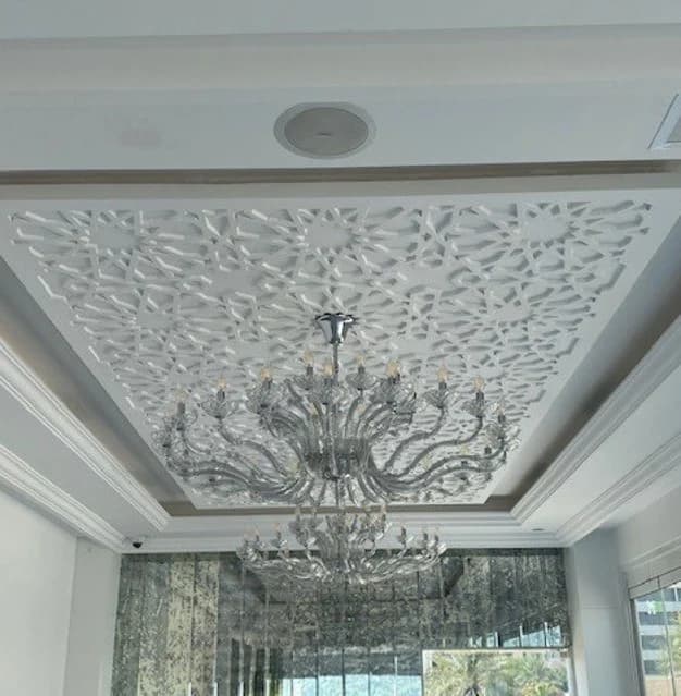 Ornamental ceiling relief, a crystal chandelier and reflective wall finishes.