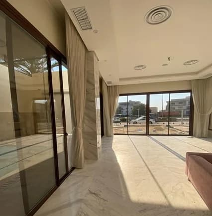 Full-height glazing brings daylight onto stone flooring and recessed ceiling details.