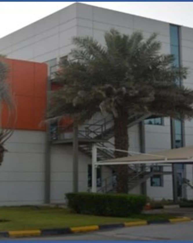 Glazed façades, coloured cladding and landscaped planting at the building entrance.