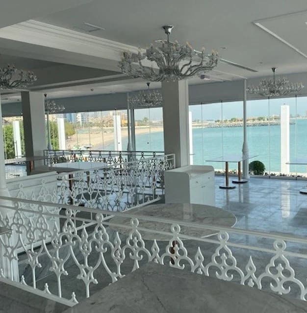 Decorative screens, chandeliers and large windows overlooking the water.
