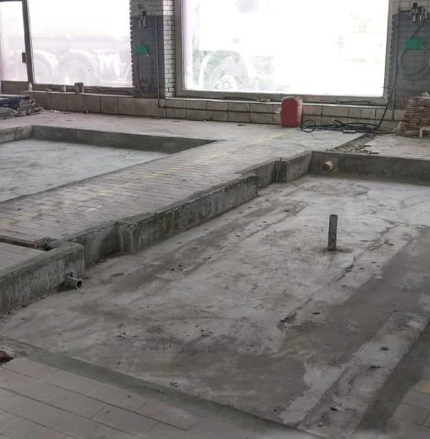 Floor preparation and raised concrete edges during interior construction.